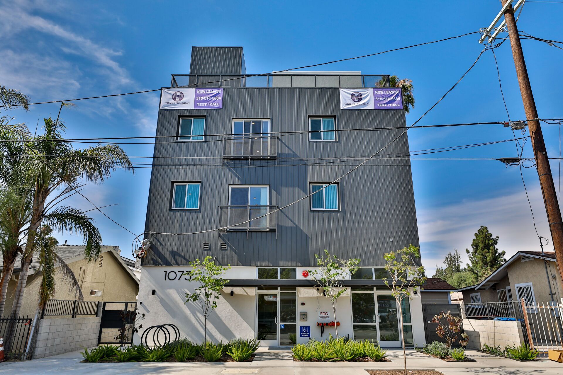This image shows triple story building and electricity wires in front of home