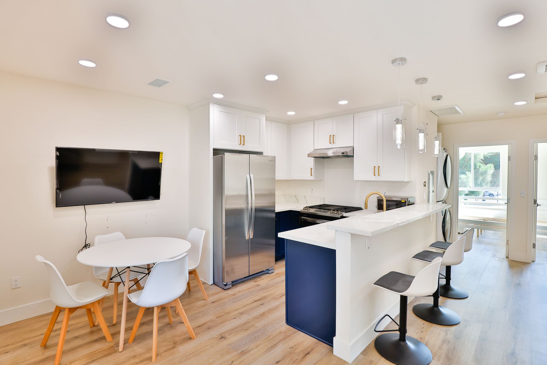 This image shows the kitchen with a table and chairs with having white theme.
