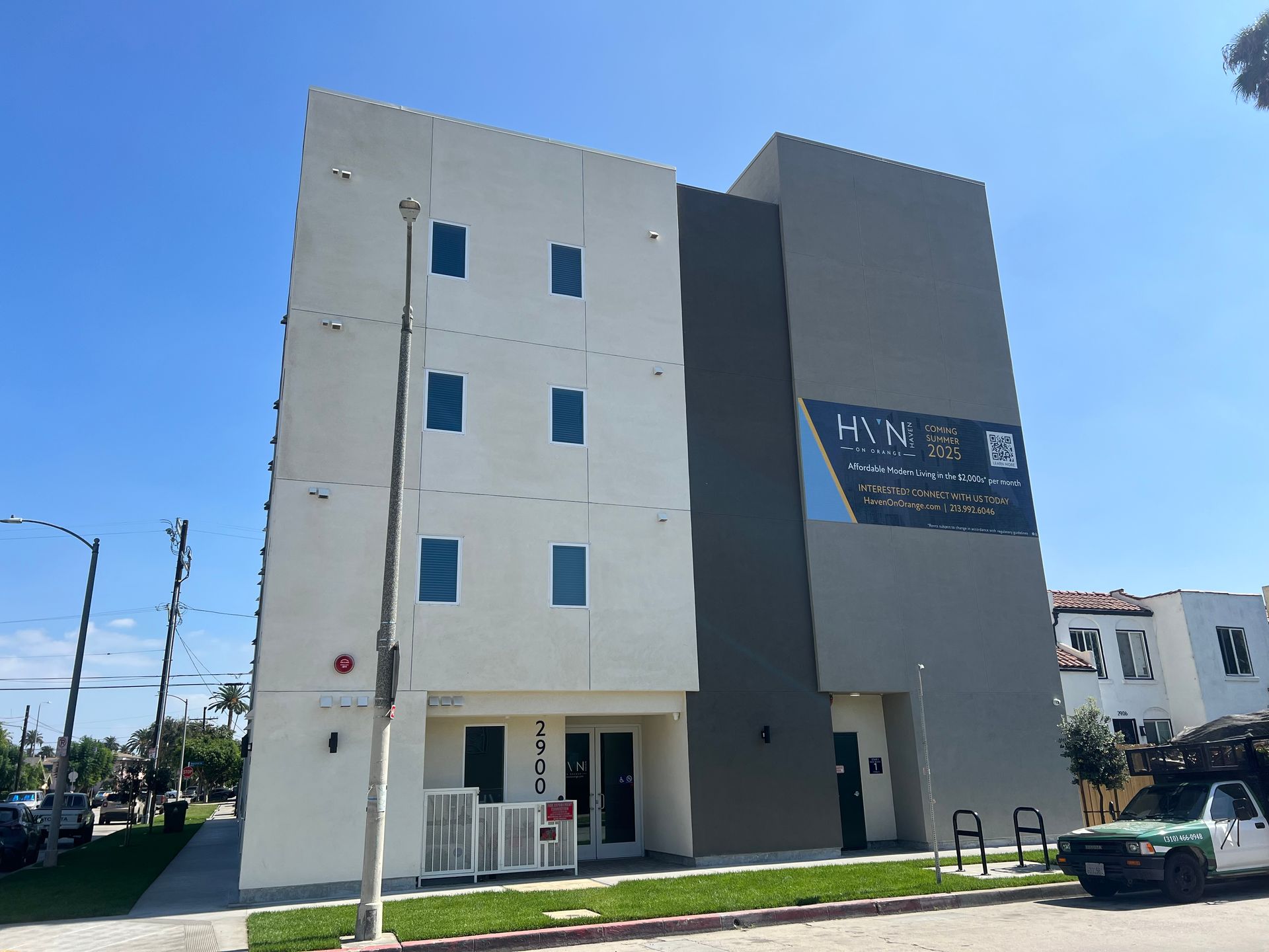 A modern three-story building with white and dark gray exterior walls under a clear blue sky.