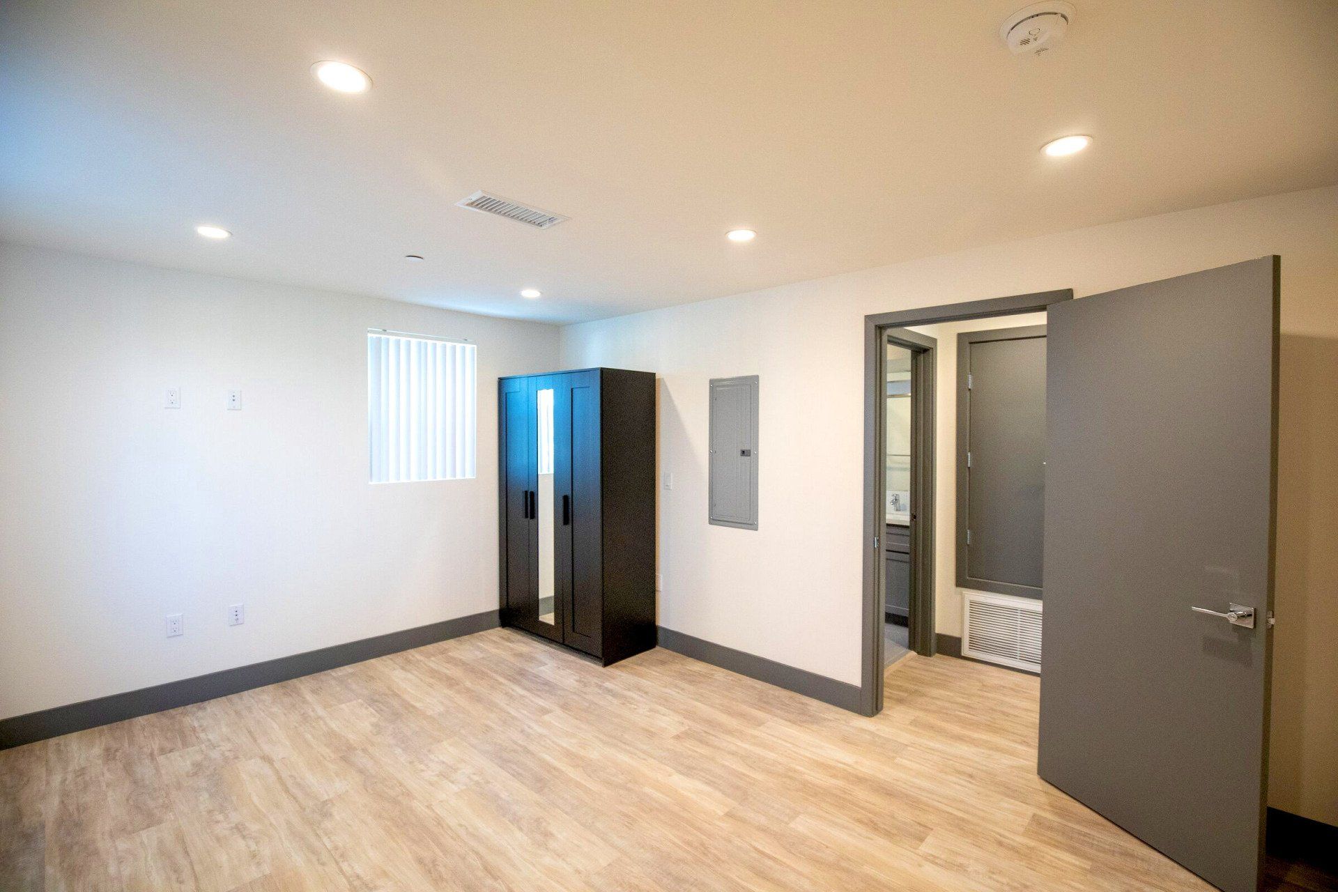 This image showing a spacious room with one window and a small cupboard in it.