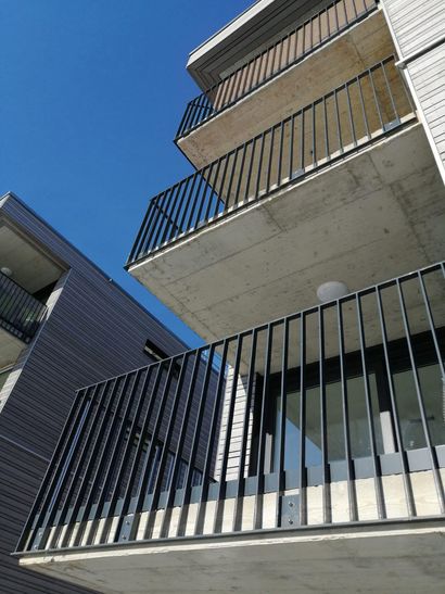 Balconi di appartamenti moderni sullo sfondo di un cielo azzurro, con ringhiere nere e facciate in cemento bianco