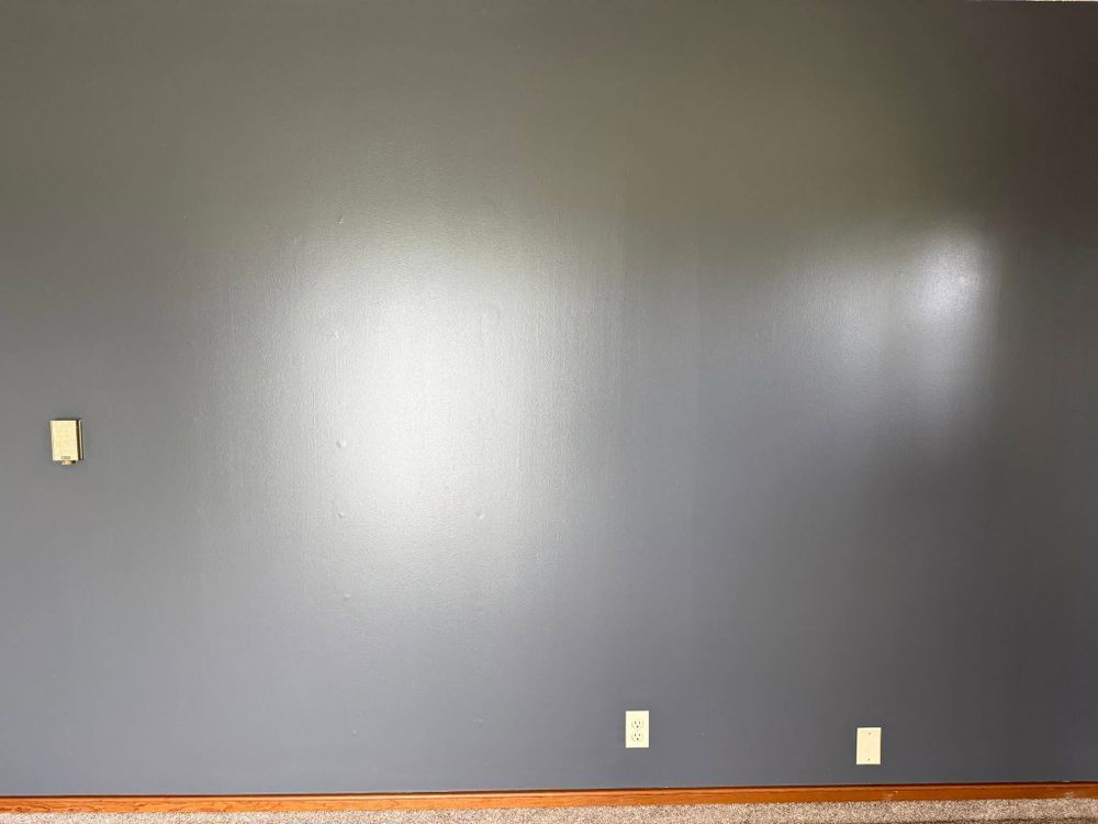 Empty gray wall with three electrical outlets and a bright glare spot