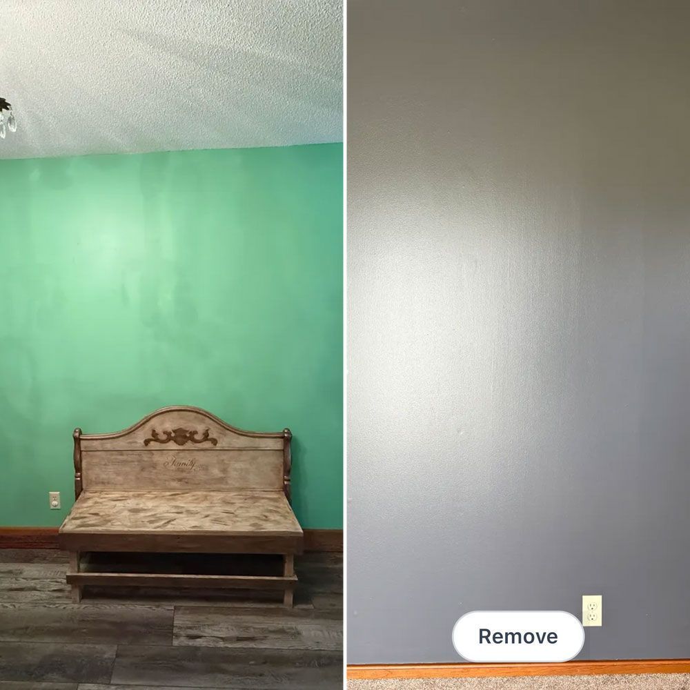Wooden bed against a teal wall beside a blank gray wall in a sparsely furnished room