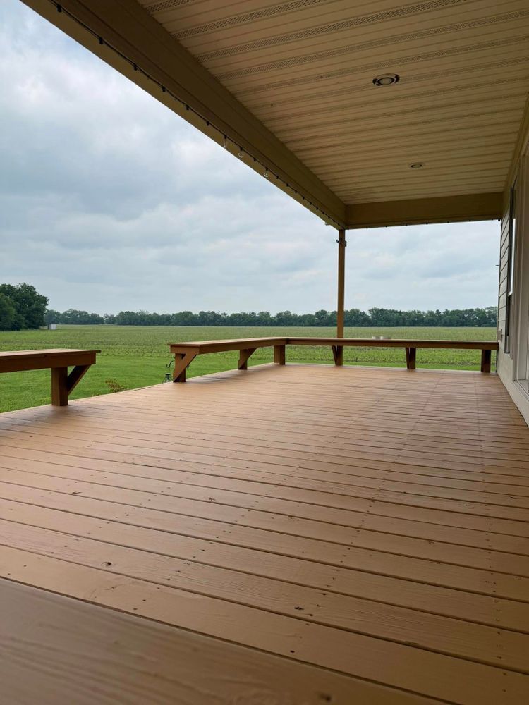 Covered wooden deck overlooking a grassy field under a cloudy sky