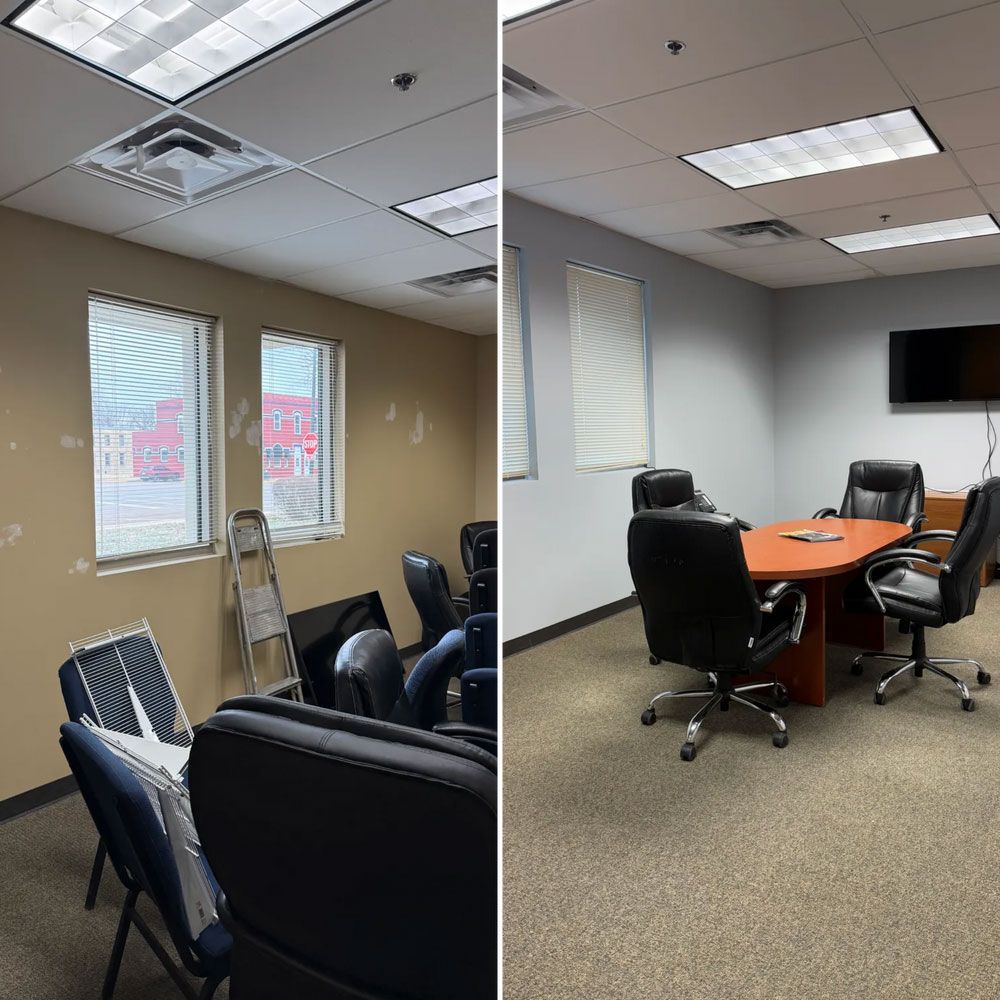 Empty office conference room with black chairs, orange table, wall-mounted TV, and windows with blinds.