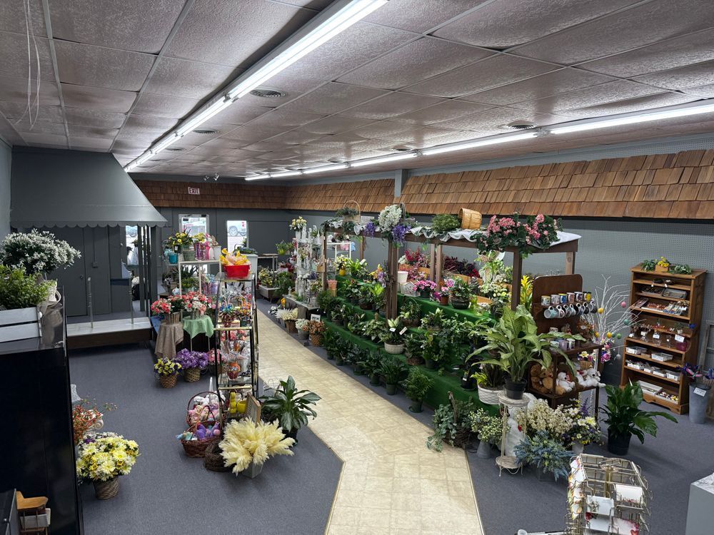 Flower shop aisle with colorful potted plants and floral displays under bright indoor lighting