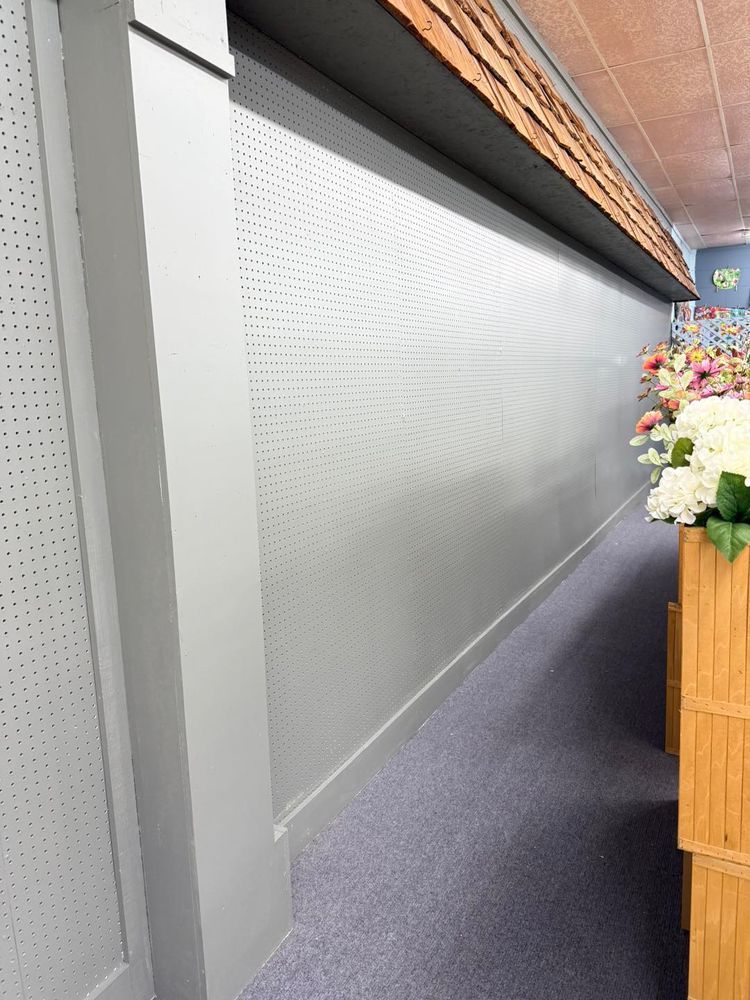 Narrow indoor hallway with frosted glass wall panels, gray carpet, and flowers on a wooden counter.