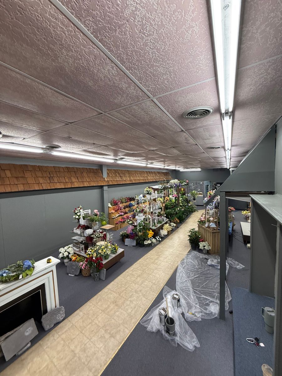 Indoor floral shop aisle with many bouquets and potted plants under fluorescent lights