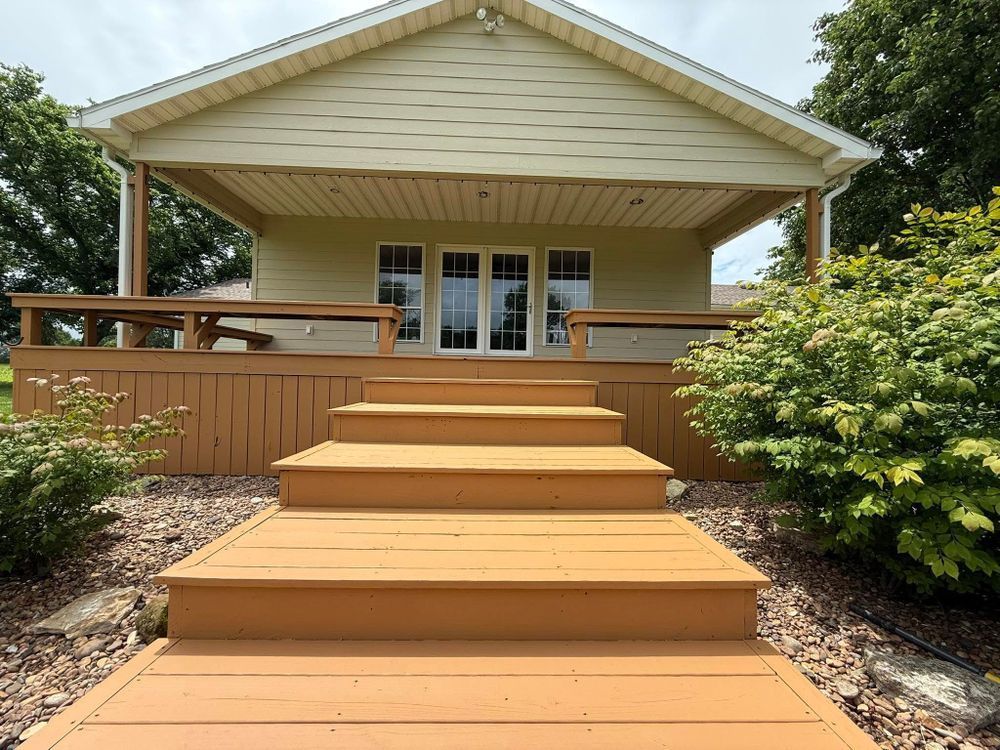 Wooden front porch with wide steps leading to a covered entry and white French doors