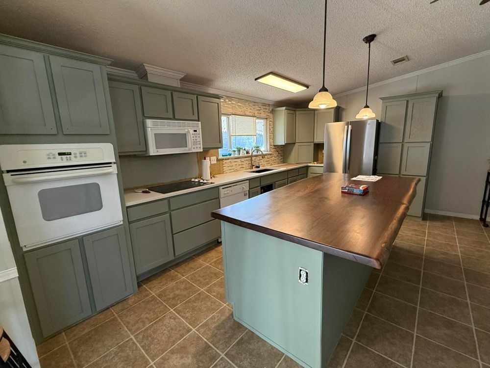 Spacious kitchen with sage cabinets, wood island, tiled floor, and stainless steel refrigerator