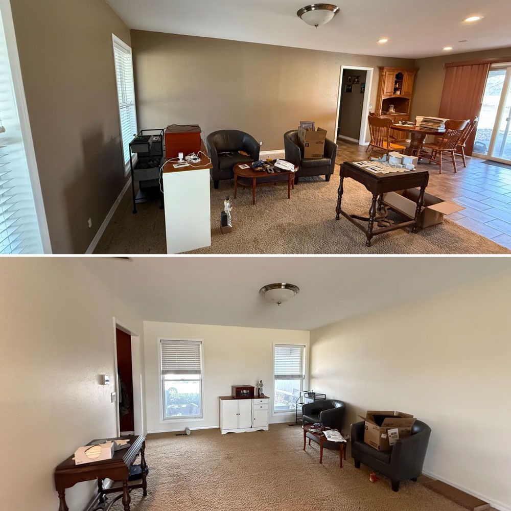 Empty living room with beige walls, scattered furniture, and a dining area in the background