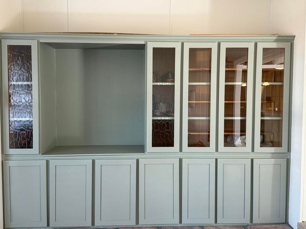 White built-in wall cabinet with open center shelf and glass-front display doors above closed lower cabinets.