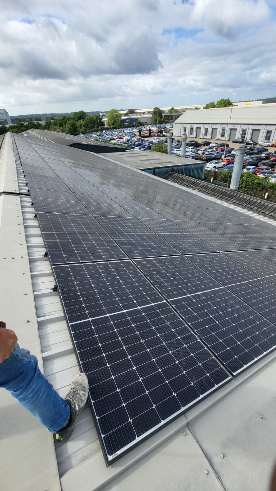 A person is standing on top of a roof with solar panels on it.