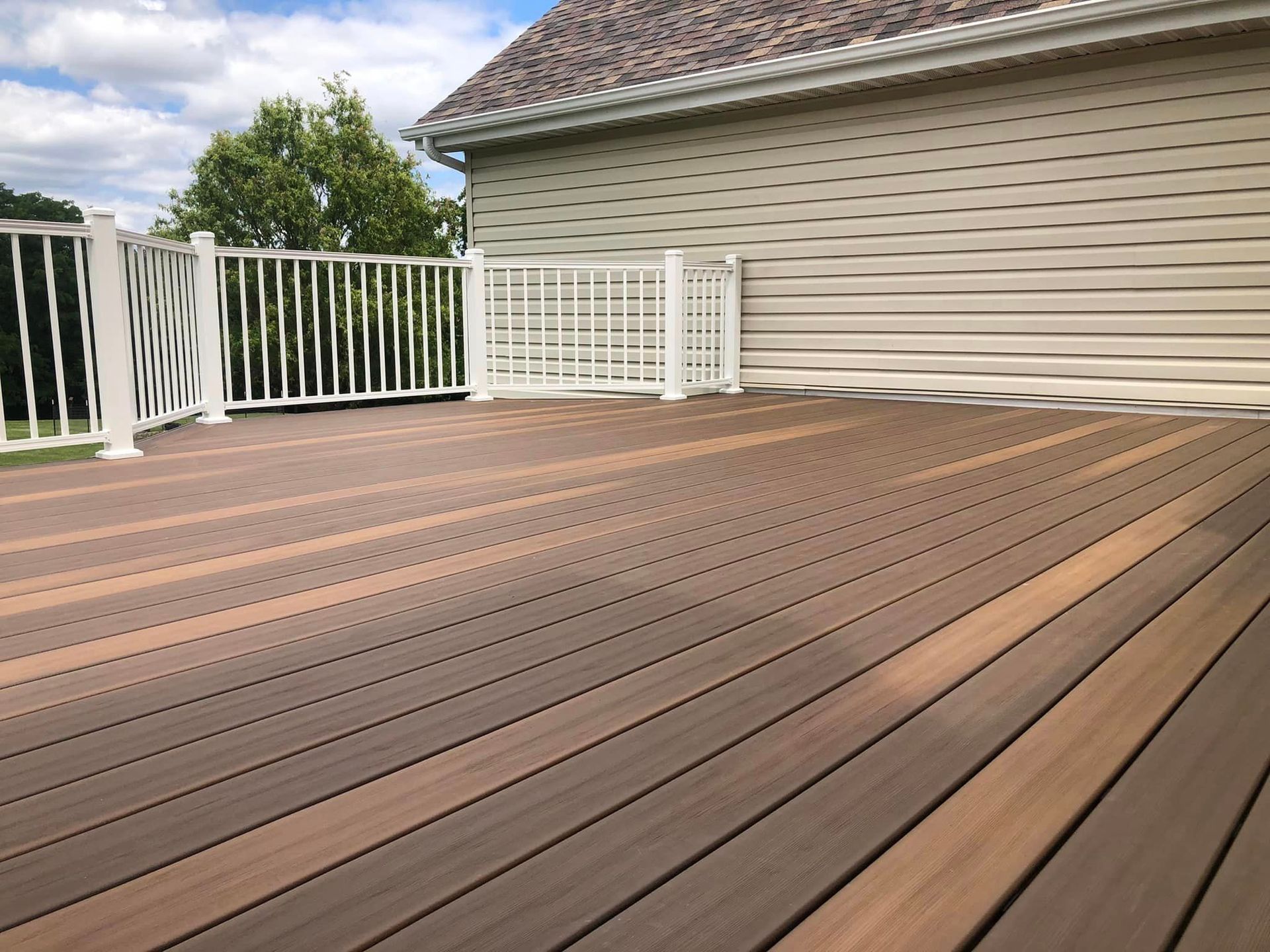 Composite deck with white railing next to a house with beige siding.