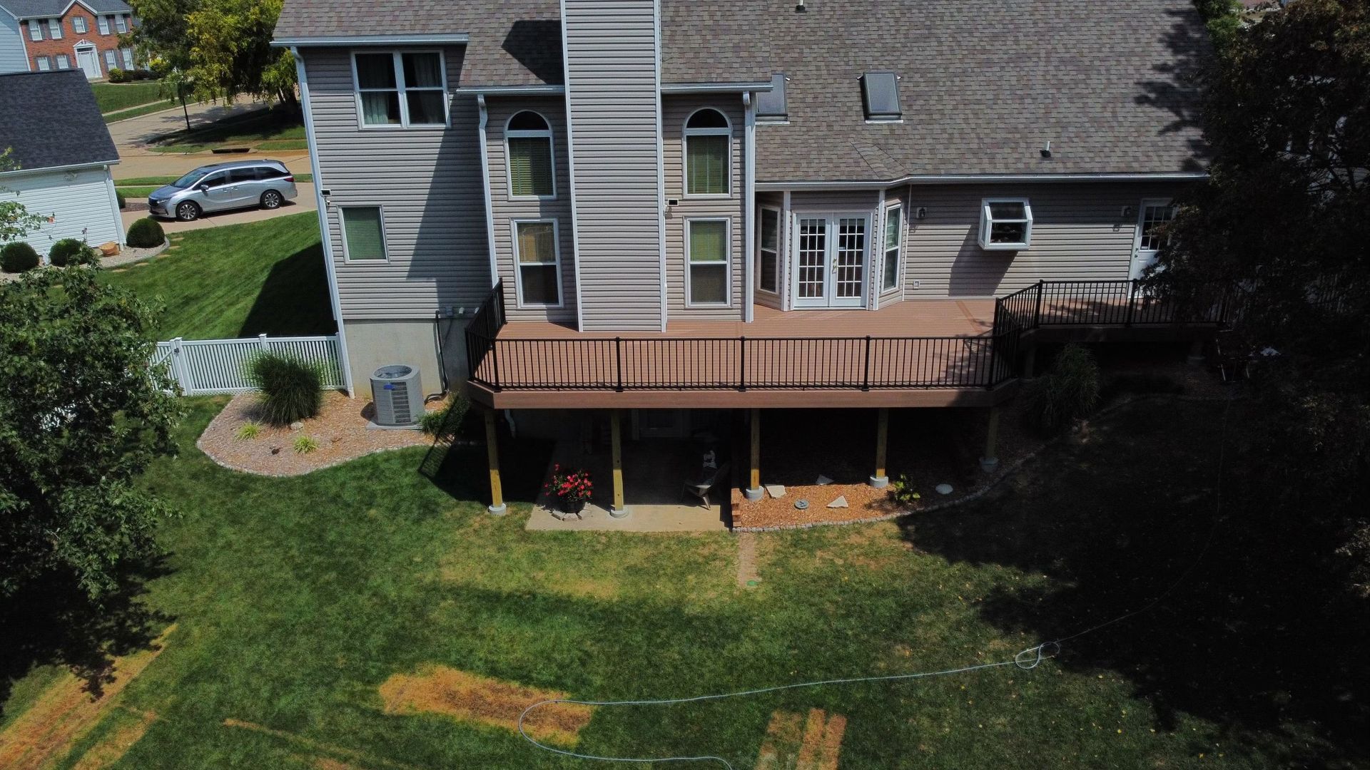Rear view of a two-story house with a wooden deck and a grassy backyard.