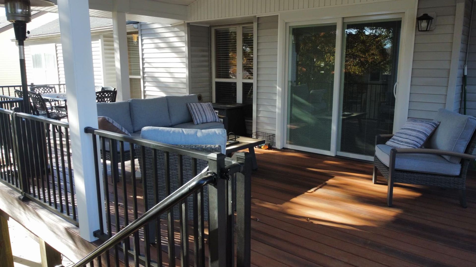 Covered deck with outdoor furniture, including a couch and chair, and a railing.