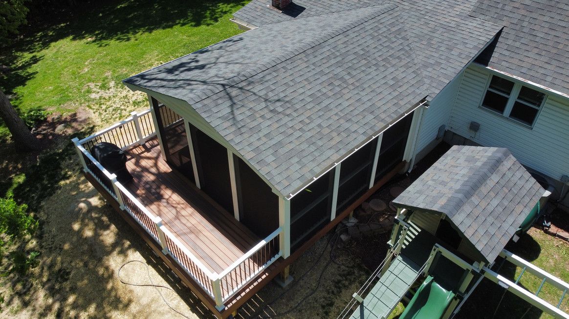 Overhead view of a house with a screened porch and attached deck, next to a playset.