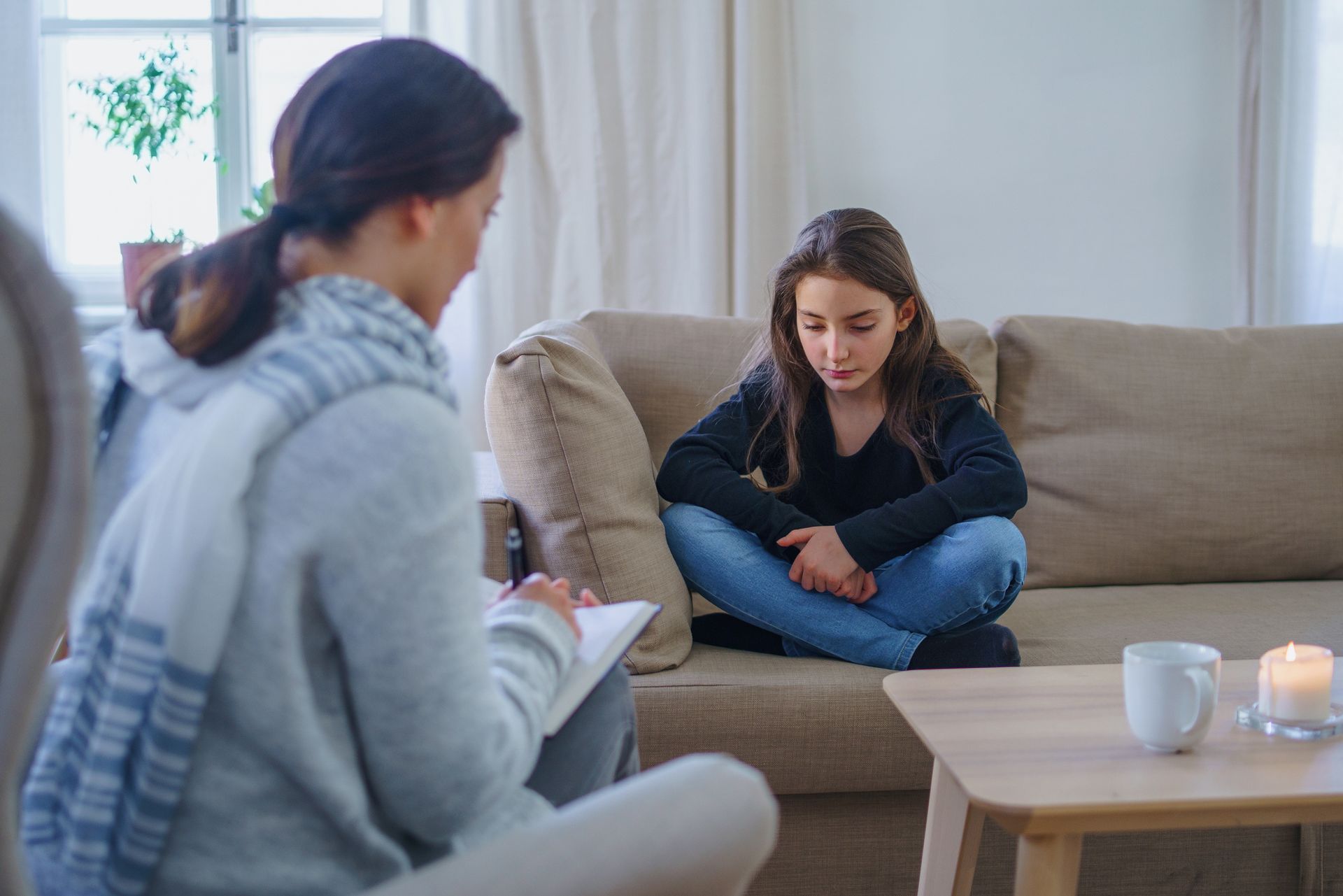 A Person Writing on A Notepad Sits Across from A Person on A Couch — Covington, KY — Mebs Counseling A Person Writing on A Notepad Sits Across from A Person on A Couch — Covington, KY — Mebs Counseling