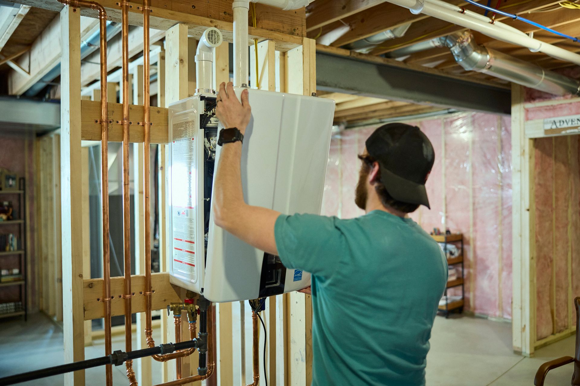 Person installing an electrical panel in a wood-framed basement under construction