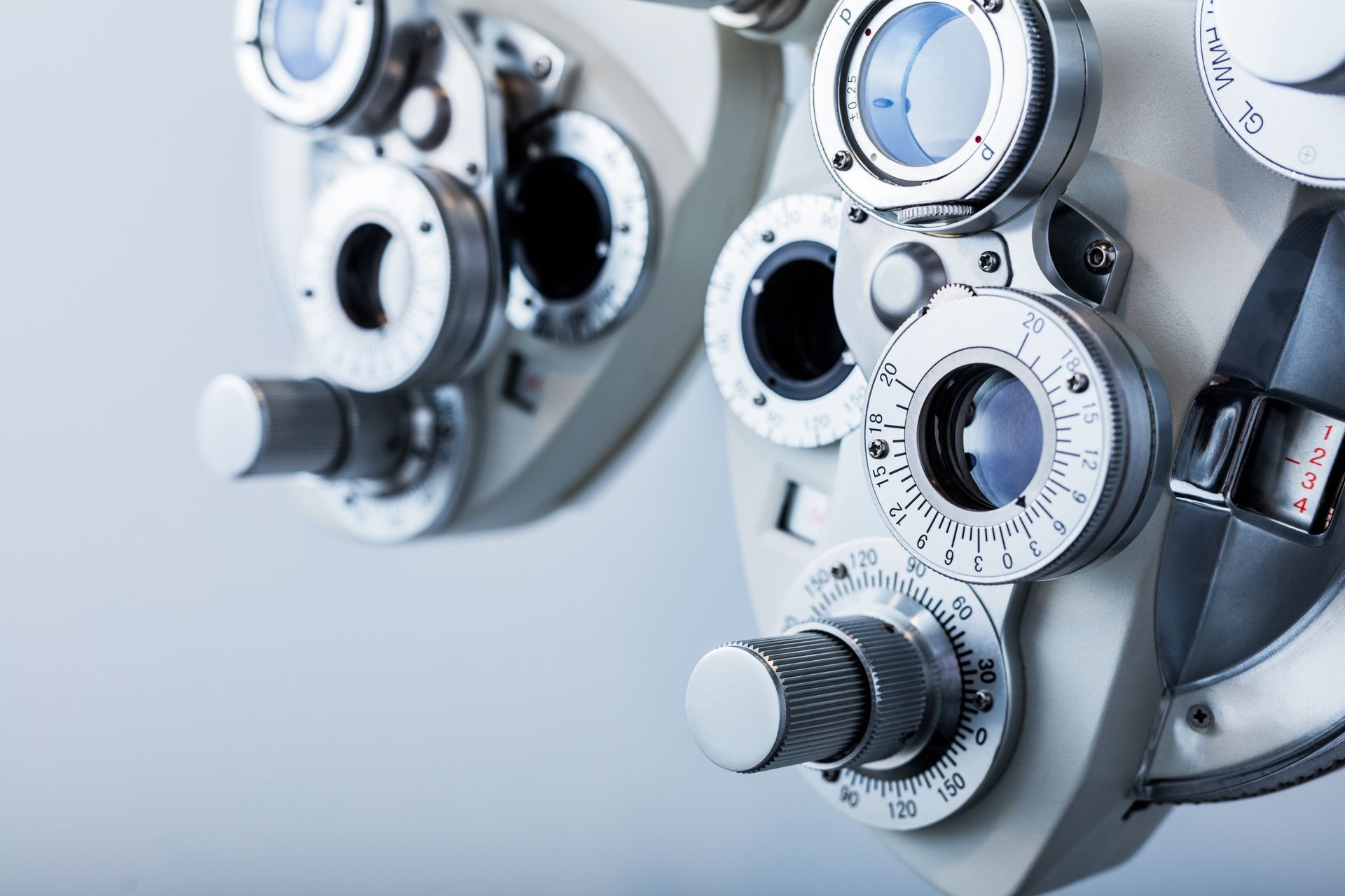 Close-up of an eye exam phoropter with circular lens dials and white metal components