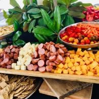 Colorful display of assorted cheese cubes, cherry tomatoes, and green leaves on wooden trays