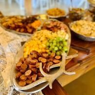 Buffet table with assorted appetizers and fruit arranged in trays on a wooden serving board