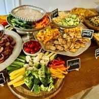 Assorted vegetable platters and dips on a buffet table with labeled dishes