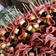 Skewers of assorted olives and wrapped cheese cubes on a platter