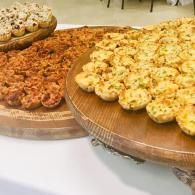 Assorted bite-sized savory pastries on wooden serving trays at a buffet table