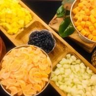 Assorted fruit bowls with sliced pineapple, melon, blueberries, and orange segments on a buffet table