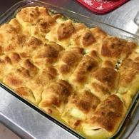 Golden-brown baked bread rolls in a glass dish on a metal tray