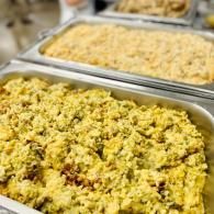Trays of yellow rice or seasoned grains at a buffet, with one tray in the foreground