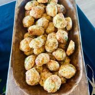A wooden tray filled with golden-brown baked rolls or dough balls.