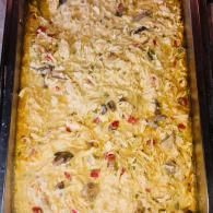 Tray of creamy baked pasta with melted cheese and red pepper pieces