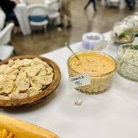 Buffet table with tortilla chips and a creamy orange dip in a glass bowl at an indoor event