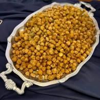 Silver tray filled with golden roasted chickpeas on a dark cloth background