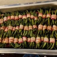 Tray of green beans bundled with bacon in rows on a metal pan