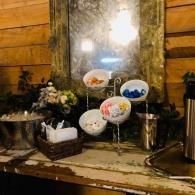 Dessert display with assorted candy bowls, flowers, and a mirror on a rustic wooden table.
