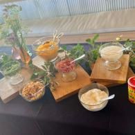 Assorted snacks and drinks on a table with black tablecloth and wooden trays at an indoor buffet