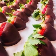Chocolate-covered strawberries arranged in rows on a white surface