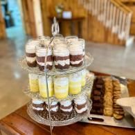 Tiered dessert stand with layered parfait cups and pastries on a table in a café