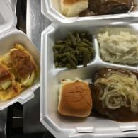 Assorted takeout meal trays with mashed potatoes, green beans, bread, and sliced meatloaf.