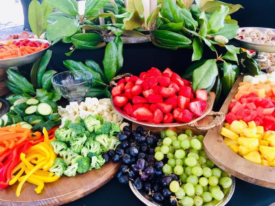 Colorful fruit and vegetable display with berries, grapes, peppers, and leafy greens arranged in bowls