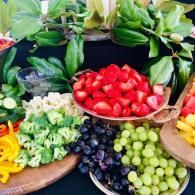Assorted fresh fruits and vegetables arranged in bowls on a market-style display.