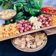 Assorted sliced meats, cheeses, and crackers arranged on platters and trays at a buffet table