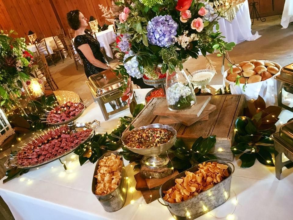 Buffet table with flowers, fruit, and appetizers at a warm-lit indoor celebration