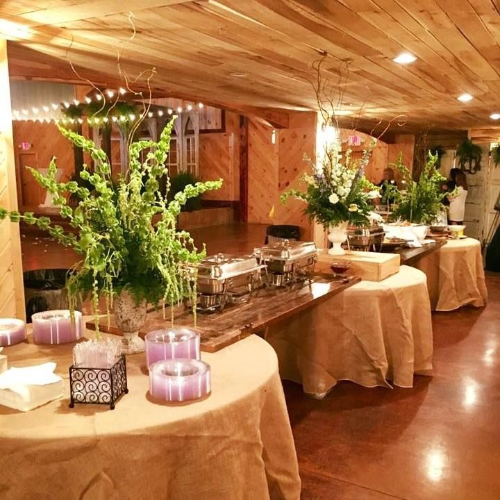 Decorated buffet table with flowers and candles in a warmly lit event hall