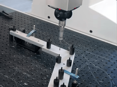 A machine is being used to measure a piece of metal on a table.
