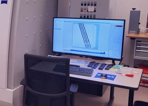 A computer monitor is sitting on top of a desk next to a chair.
