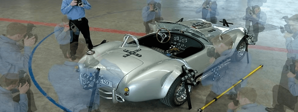 A man is taking a picture of a silver sports car.